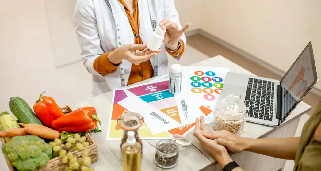 Nutricionista organizando alimentos e anotações ao lado de notebook